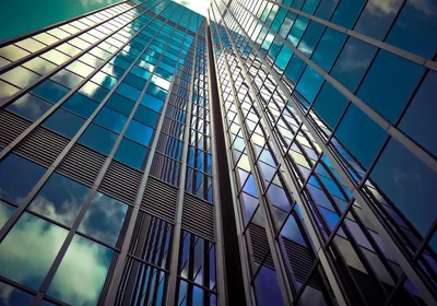 Looking up at a glass skyscraper reflecting clouds