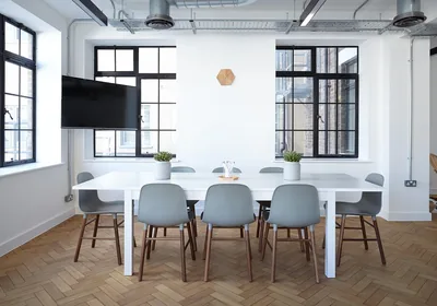 A bright meeting room with a white table and grey chairs